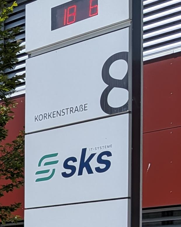 Firmenschild an der Korkenstraße 8: Uhr, Hausnummer und das Logo der SKS GmbH